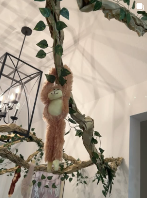 Plush monkey hanging from a leafy vine installation